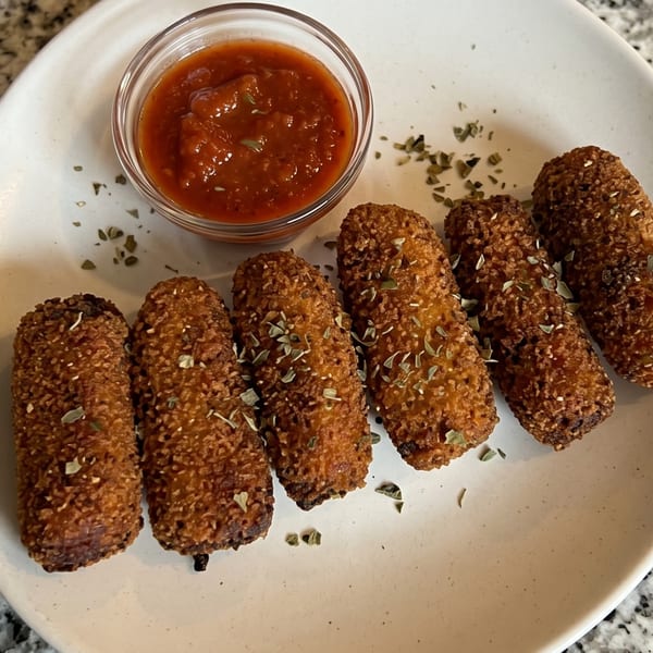 Six crispy mozzarella sticks with dried herbs, served with a side of marinara sauce.
